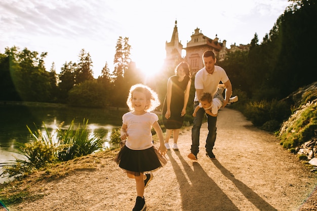 Beau jeune père et belle mère dans la nature d'été ensoleillée jouant avec leurs petits enfants mignons