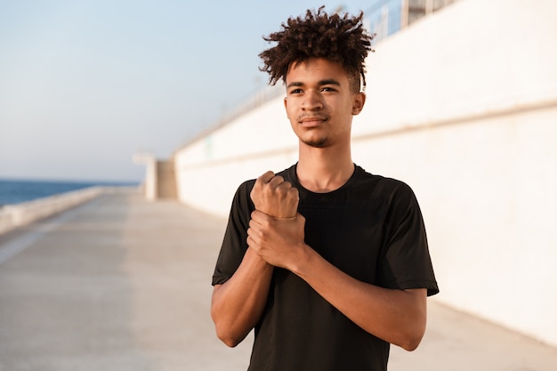 Beau jeune sportif posant à l'extérieur sur la plage