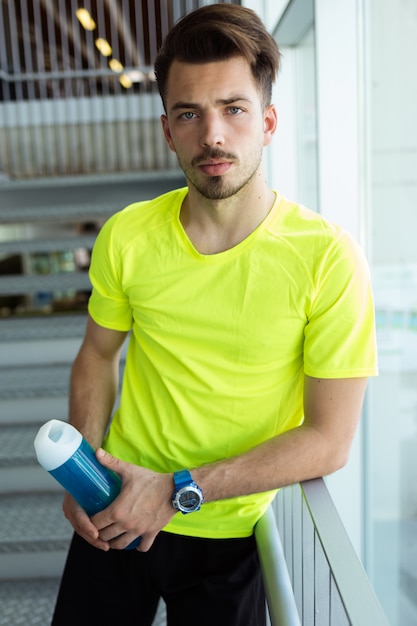 Beau jeune sportif se relaxant après la classe en gymnase.