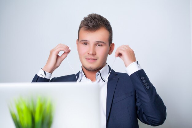 Beau jeune travailleur travaillant dans un bureau d'entreprise avec des documents et un ordinateur portable