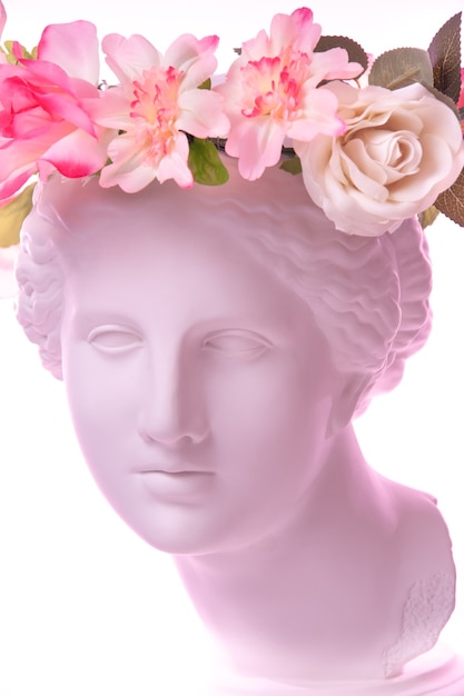 Beau jeune visage féminin et fleurs colorées. Buste antique en plâtre de Vénus de Milo dans une couronne de fleurs. Fille modèle printemps et été de beauté avec bouquet frais.