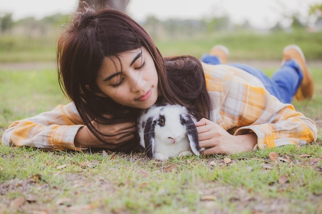 Beau joli portrait de jeune femme asiatique avec un lapin mignon dans le concept de soins aux animaux de compagnie et aux animaux heureux femme tenant un lapin sur le terrain extérieur de la nature avec le concept de pâques d'amitié