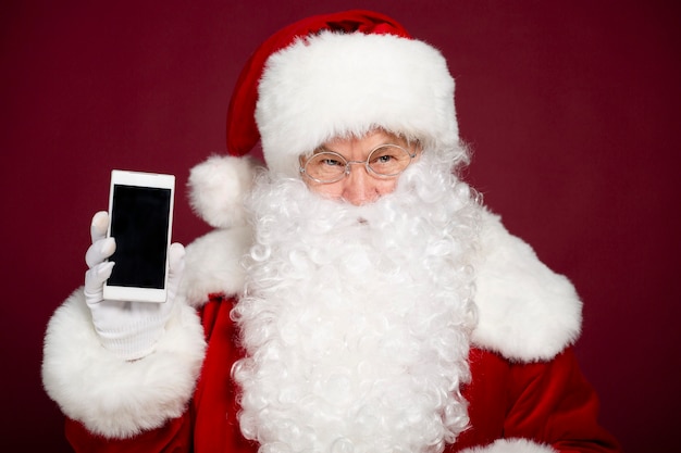 Beau joyeux père Noël montre l'écran blanc d'un smartphone