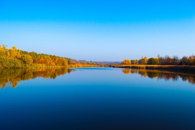 Beau lac avec reflet de ciel bleu et arbres d'automne