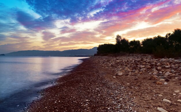 Beau lever de soleil coloré à la mer avec des nuages dramatiques et bord de mer avec des rochers