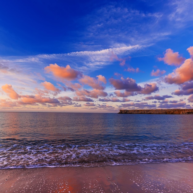 Beau lever de soleil coloré sur la mer avec des nuages roses spectaculaires sur un ciel bleu et des vagues douces. Fond de voyage en plein air naturel du monde de la beauté