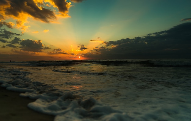 Beau lever de soleil sur la mer bleue. rayons lumineux du soleil. vagues sur la plage.
