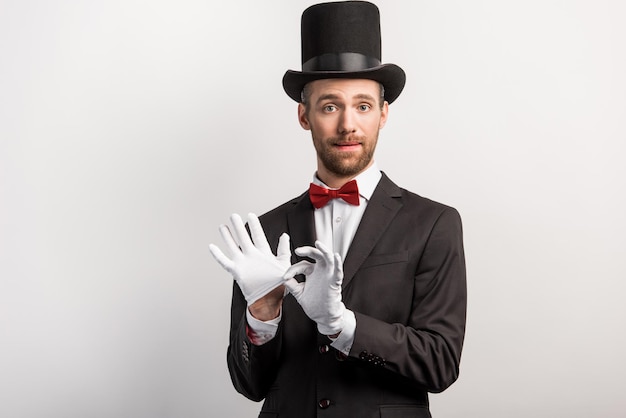 Beau magicien enlevant des gants isolés sur gris