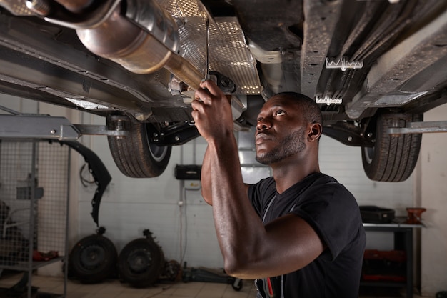 Beau mâle africain réparant le bas de la voiture