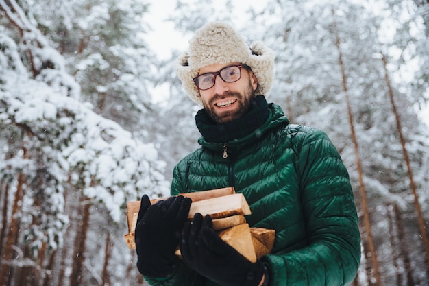 Beau mâle barbu portant des lunettes et un chapeau chaud avec anorak