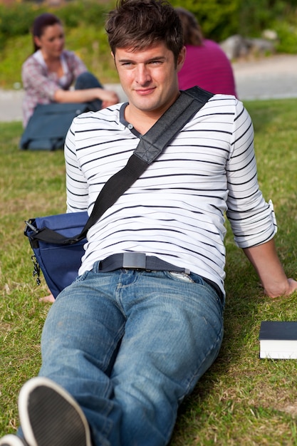 Beau mâle étudiant couché sur l&#39;herbe avec son cartable