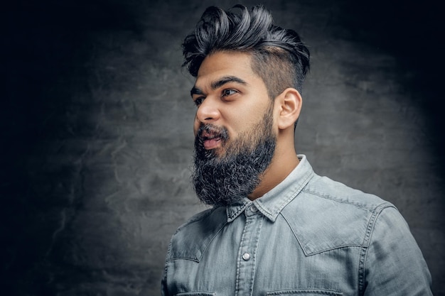 Un beau mâle indien barbu vêtu d'une chemise polaire sur fond gris vignette.