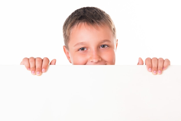 Un beau mâle souriant posant derrière un panneau blanc isolé sur fond blanc.