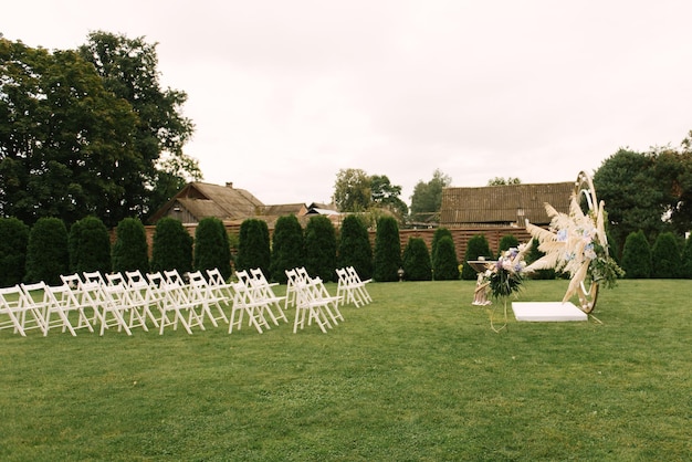 Beau mariage pour une cérémonie de mariage dans la nature décorée de fleurs et beaucoup de chaises blanches pour la décoration de mariage des invités