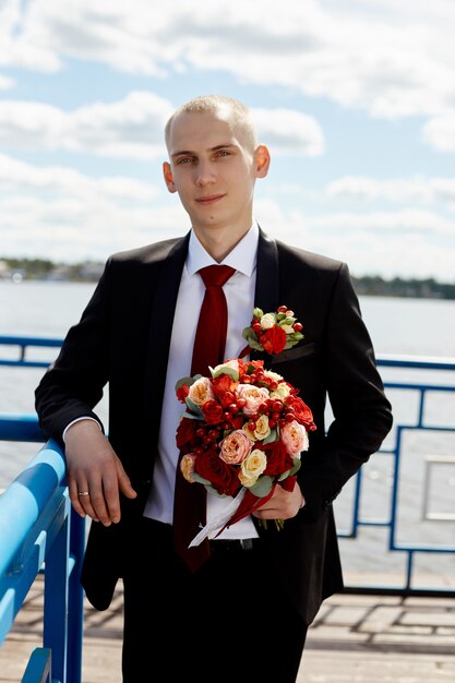 Beau marié aimant avec bouquet floral