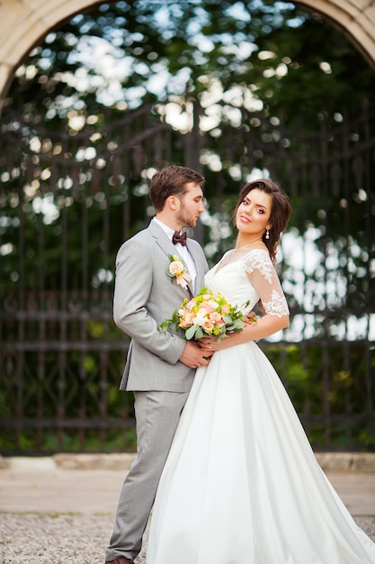 Beau Marié étreignant Belle Mariée Avec Bouquet Dans Un Parc Européen Romantique