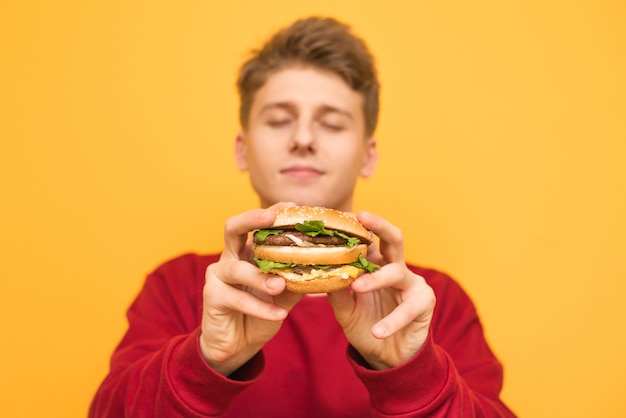 Beau Mec Aux Yeux Fermés Montre Un Délicieux Grand Hamburger à La Caméra