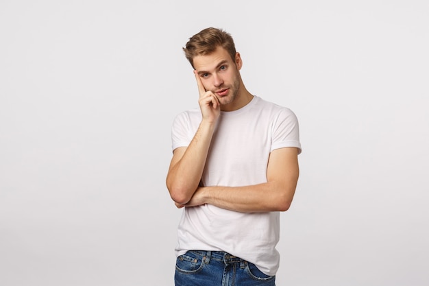 Beau mec blond aux yeux bleus et pensée de T-shirt blanc