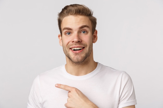 Beau mec blond aux yeux bleus pointant sur le côté