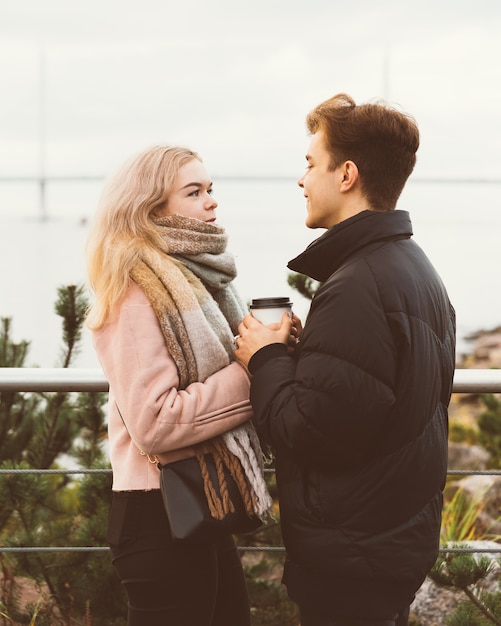 Photo beau mec brune et jolie fille blonde boivent du café et parlent à la date. adolescents aimants