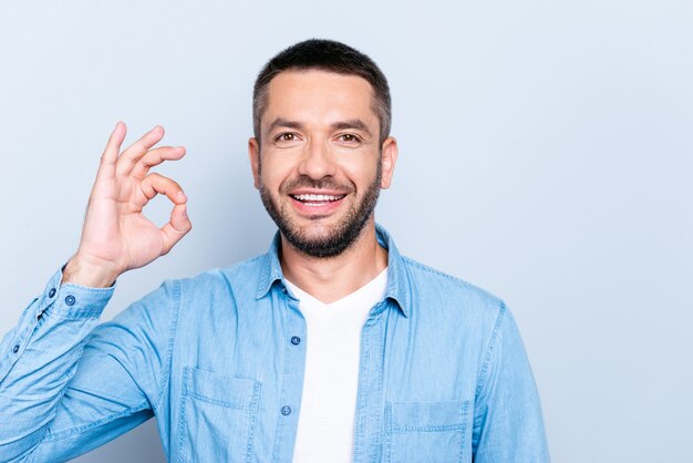 Beau mec avec une chemise bleue posant contre le mur bleu clair