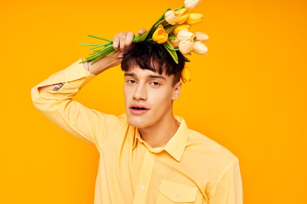 Beau mec avec une coiffure à la mode en chemises jaunes avec des fleurs fond jaune inchangé