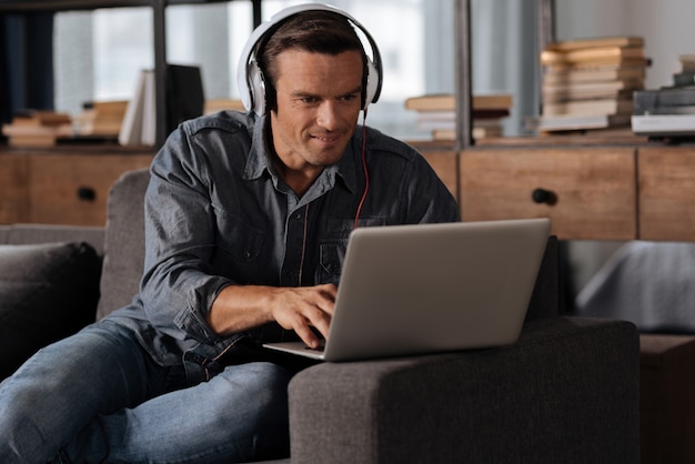 Beau mec cool intelligent, écouter de la musique et taper quelque chose sur son ordinateur tout en étant indépendant