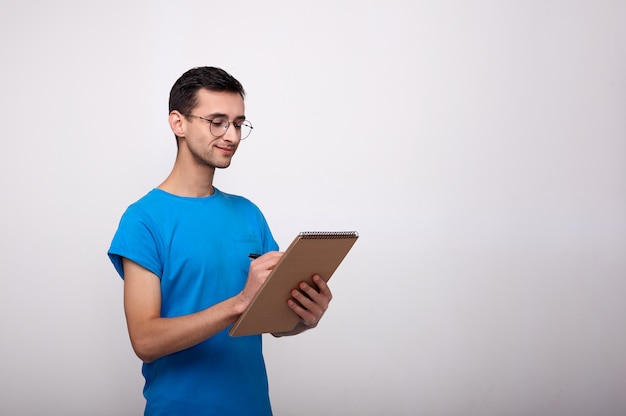 Un beau mec écrit dans un cahier marron.