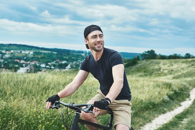 Beau mec élégant à vélo dans les montagnes