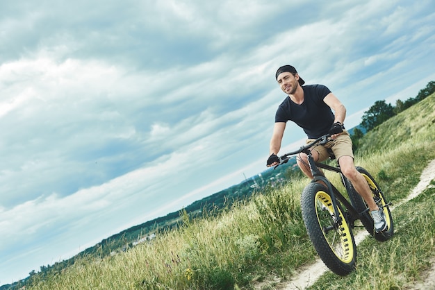 Beau mec élégant à vélo à la vue de dessous des montagnes