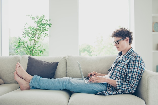 Beau mec étudiant à la maison en tapant sur un ordinateur portable