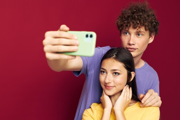 Beau mec et fille en t-shirts colorés avec un fond isolé de téléphone