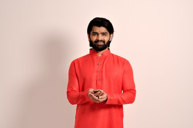 Beau mec indien tenant Diya pour Diwali et portant une kurta orange