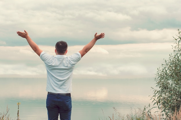 Beau mec sur le lac. Les mains en l'air. Liberté. La victoire.