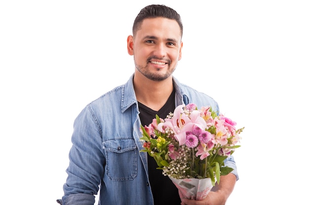 Beau mec latin tenant un bouquet de fleurs roses et se préparant à rencontrer son rendez-vous pour le dîner