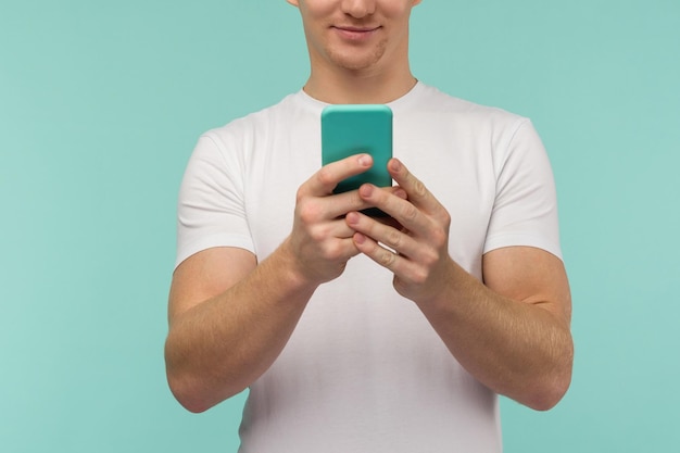 Beau mec sportif diffuse en ligne sur un smartphone sur fond bleu