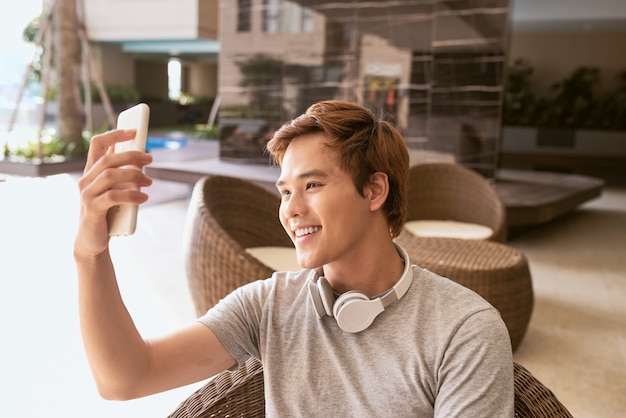 Beau mec utilisant un téléphone portable par une journée d'été ensoleillée