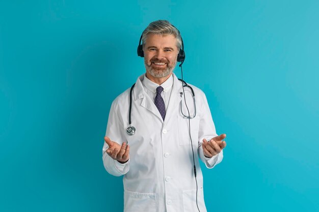 Beau médecin d'âge moyen avec casque sur fond de studio bleu