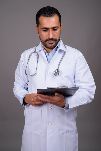 Beau médecin barbu contre le mur gris