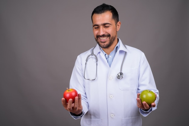 Beau médecin barbu contre le mur gris