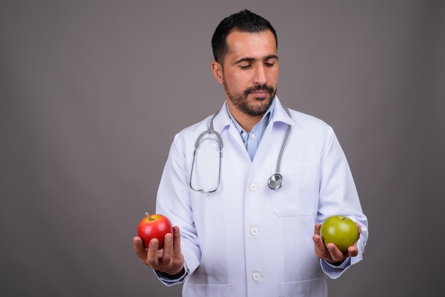 Beau médecin barbu contre le mur gris