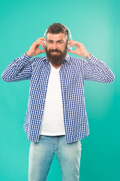 Photo beau mélomane homme dans des écouteurs sites de musique en streaming les plus branchés et les plus chauds technologie sans fil interface conviviale et grande bibliothèque de morceaux hipster avec barbe écoutant de la musique