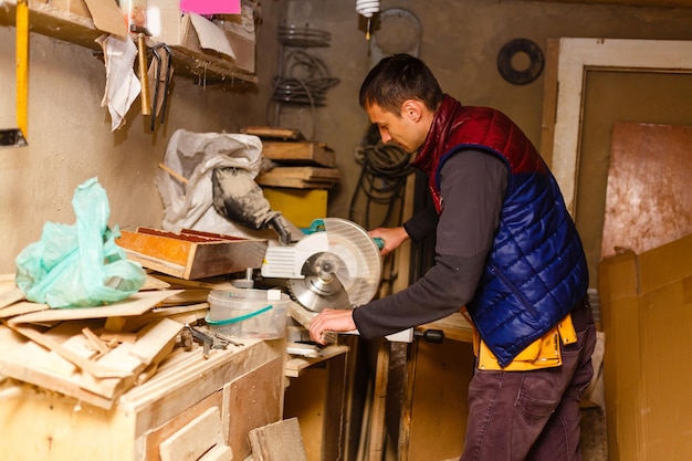 Beau menuisier travaille en menuiserie. Il est un entrepreneur prospère sur son lieu de travail.