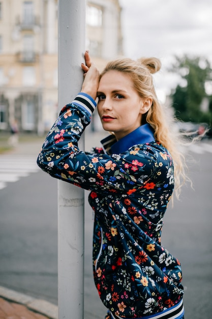 Beau modèle blond élégant en costume coloré posant dans la rue