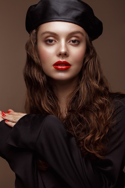 Beau modèle brune avec des boucles, un maquillage classique et des lèvres sexy. La beauté du visage. Portrait réalisé en studio.