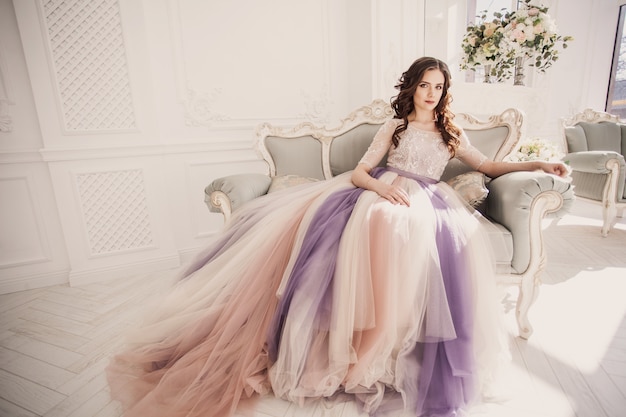 Beau modèle dans une belle robe de mariée dans un studio photo blanc. Mariée en robe de mariée de couleur.