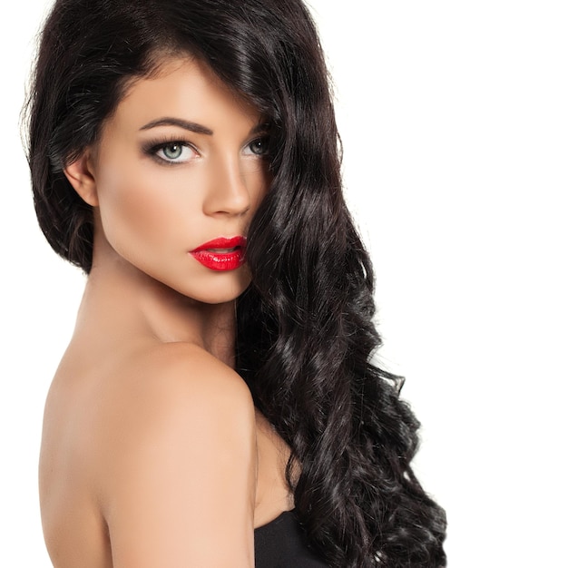 Beau modèle féminin brune avec coiffure bouclée et maquillage femme parfaite avec de longs cheveux sains sur fond blanc