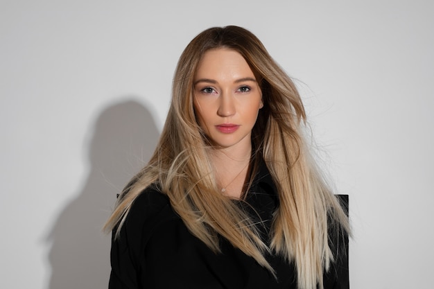 Beau modèle féminin de race blanche avec un joli visage et des cheveux blonds regarde la caméra en studio