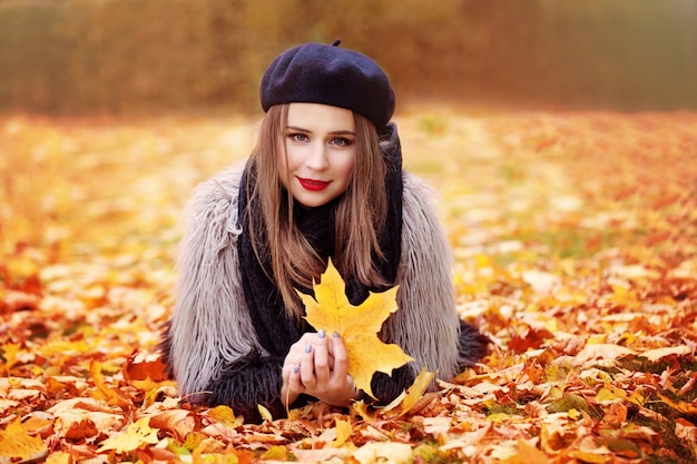 Photo beau modèle femme allongée sur les feuilles d'automne à l'extérieur
