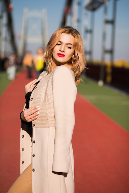 Beau modèle habillé à la mode posant dans la rue à la lumière du soleil